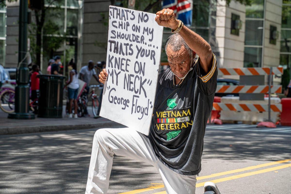 A man kneels to protest the killing of George Floyd at the Black Lives Matter mural in uptown Charlotte on June 26, 2020.
