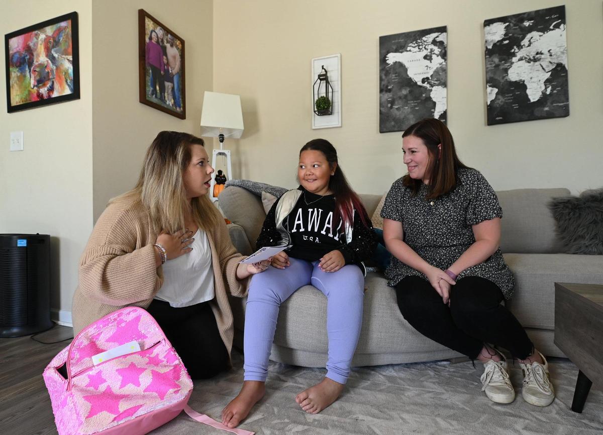 Jade Williams&nbsp;— at left, next to her daughter Sunnie and Jane's Fund executive director Lauren Harnett — at the moment she learns her family's mortgage has been paid off in full.