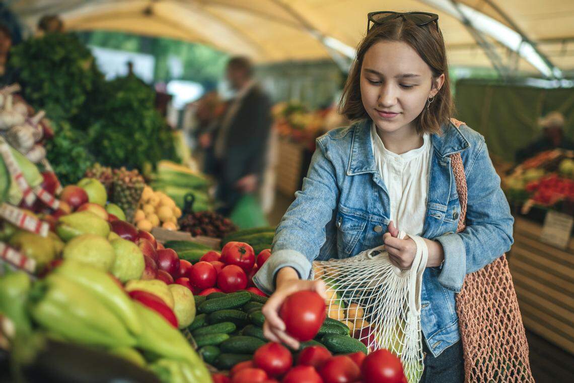 Young woman picking out fresh produce at a farmer's market.
