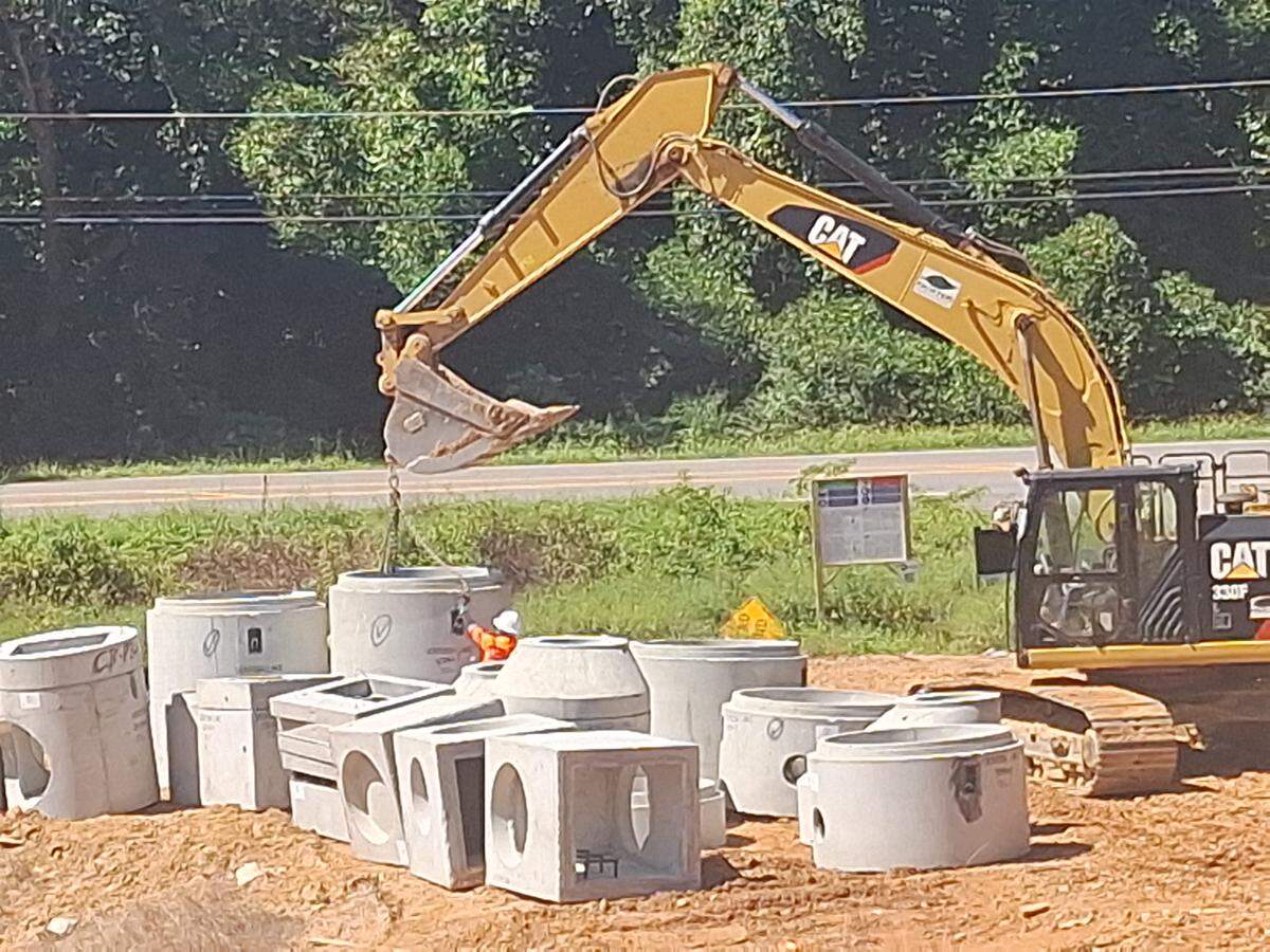 Crews on Sept. 9, 2025, use a front-end loader to lift a piece of what will be the underground drainage system for Norman Village Road in Mooresville.