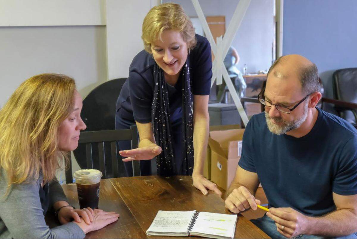 Paige Johnston Thomas (center) works with local actors Tonya Bludsworth and Shawn Halliday on scenes from the Tony Award-winning play, “Oslo,” which she is directing for Three Bone Theatre in Charlotte. The play opens May 23 at Spirit Square.
