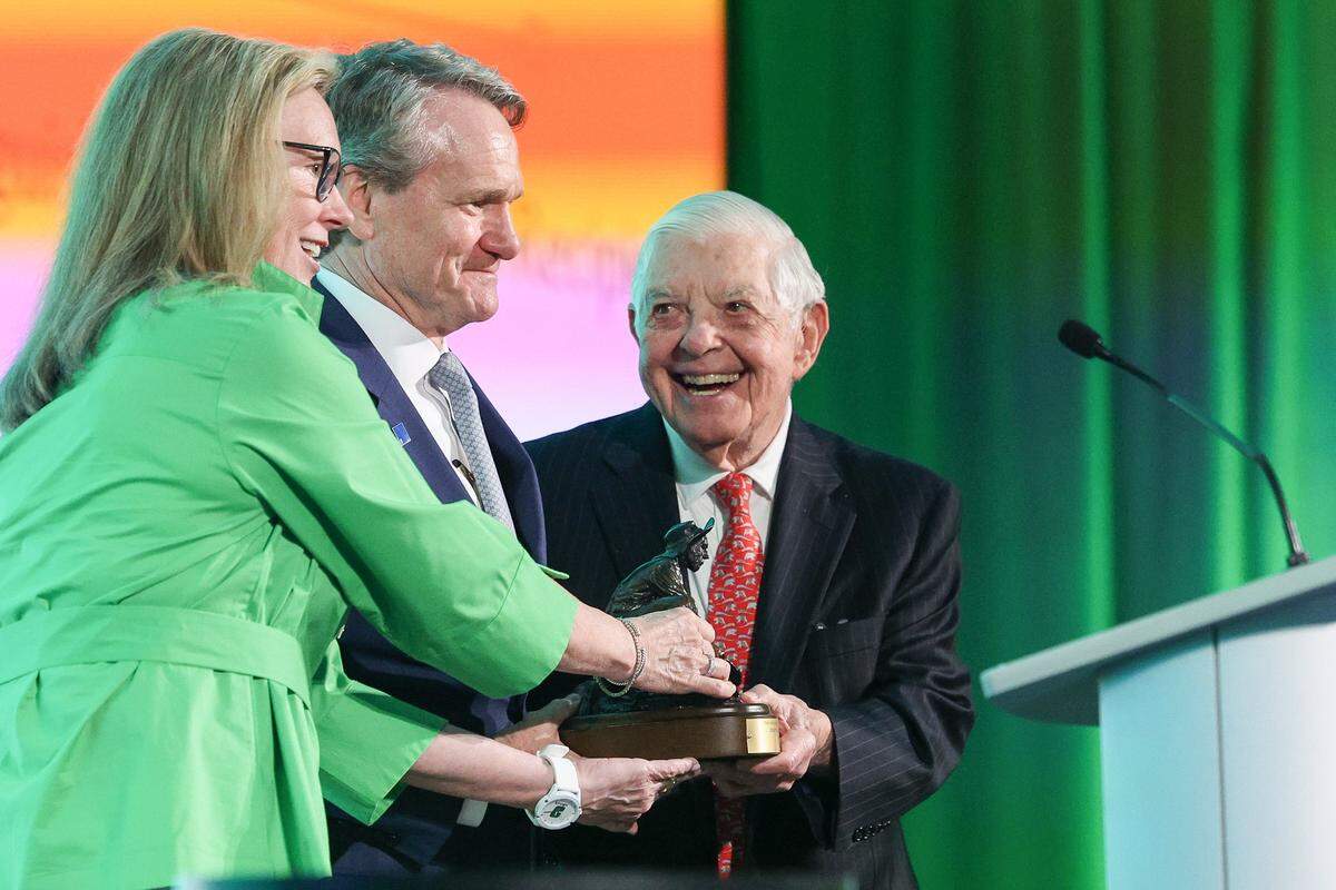 Hugh McColl, former CEO of Bank of America, far right, smiles at Brian Moynihan, Chair and CEO of Bankof America center, as he receives the Distinguished Service Award at UNC Charlotte on Monday, March 30, 2026.