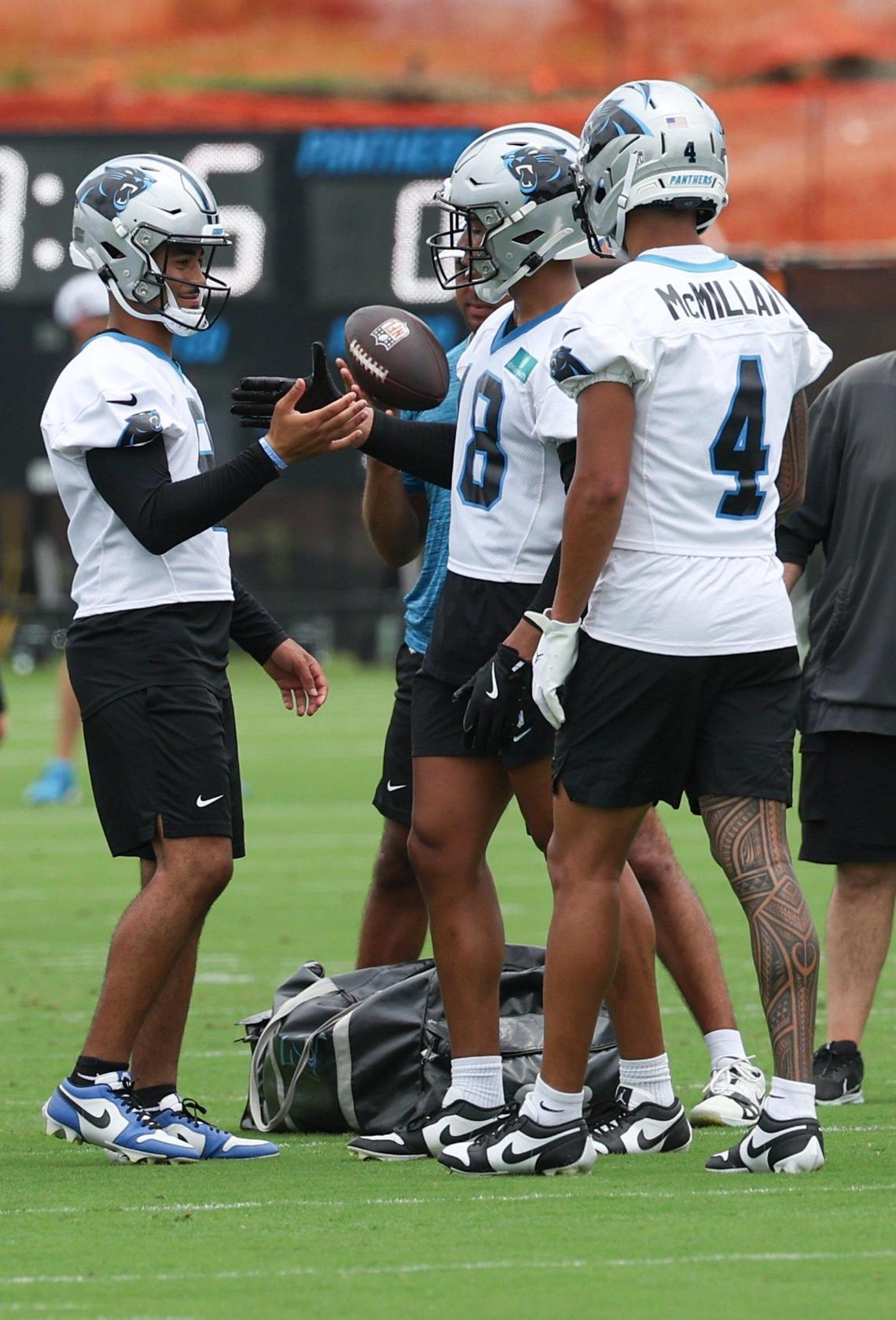Panthers quarterback Bryce Young, left, smiles while doing a special handshake with wide receiver Jalen Coker, center, before they run through passing drills during the first day of minicamp in Charlotte, NC on Tuesday, June 10, 2025.