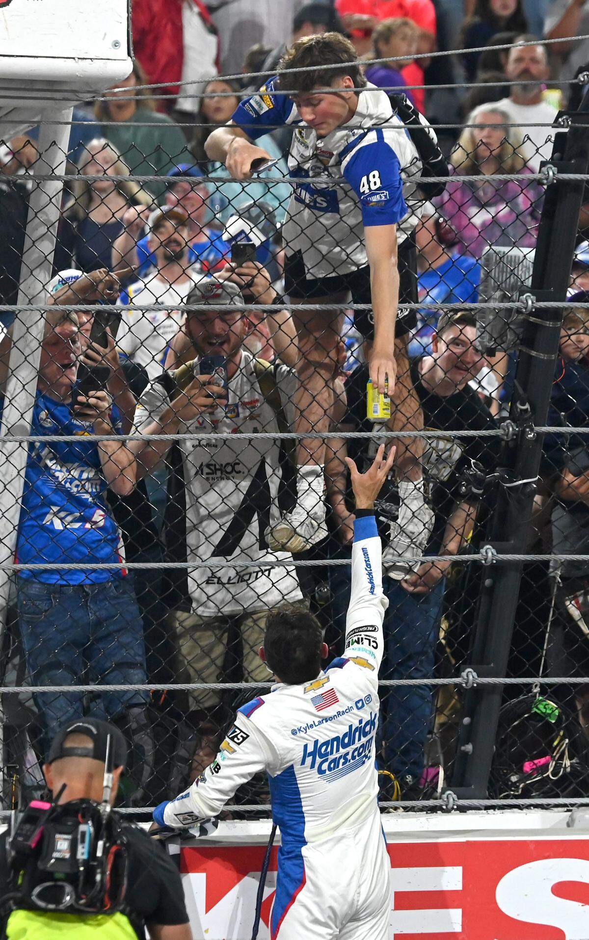 NASCAR driver Kyle Larson grabs a can from a fan after winning the NASCAR All-Star race at North Wilkesboro Speedway on Sunday, May 21, 2023.
