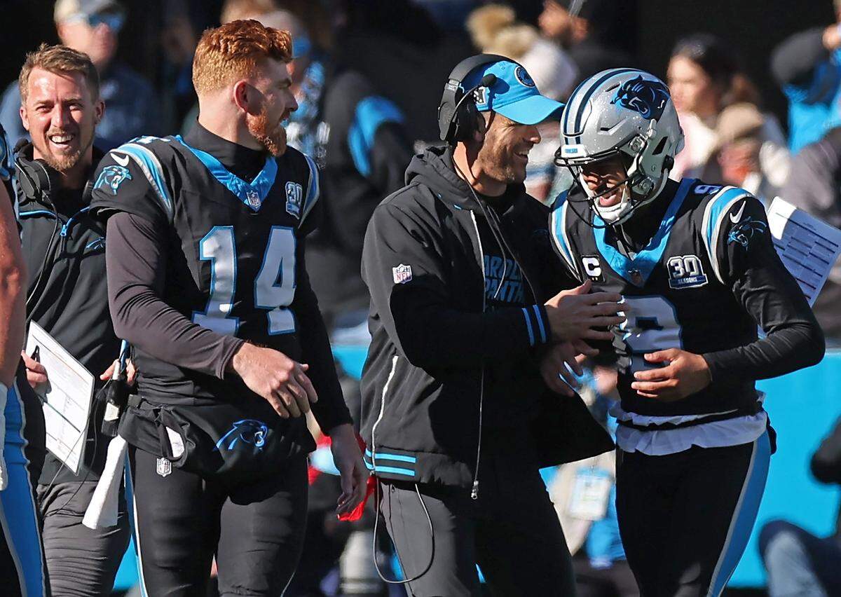 Carolina Panthers quarterback Bryce Young, right, is congratulated by head coach Dave Canales, center and quarterback Andy Dalton, left, following Young’s rushing touchdown against the Arizona Cardinals at Bank of America Stadium in Charlotte, NC on Sunday, December 22, 2024. The Panthers defeated the Cardinals 36-30 in overtime.