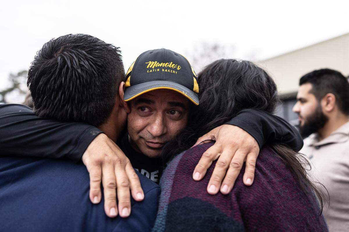 Manolo Betancur, center, hugs Charlotte Councilmember-Elect Juan Diego Mazuera Arias, left and Kelly Morales with Siembra NC during a news conference at Betancur’s bakery on Nov. 21  2025, amid federal immigration raids.