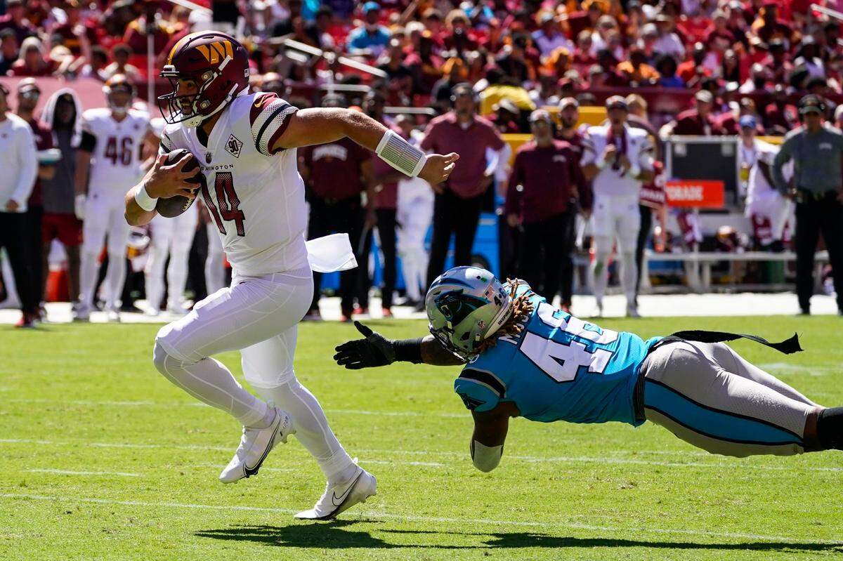 Washington Commanders quarterback Sam Howell, left, runs for a touchdown after avoiding a tackle by Carolina Panthers linebacker Arron Mosby, right, during the second half of an NFL preseason football game Saturday, Aug. 13, 2022, in Landover, Md. Howell ran for two TDs in Washington’s 23-21 loss.