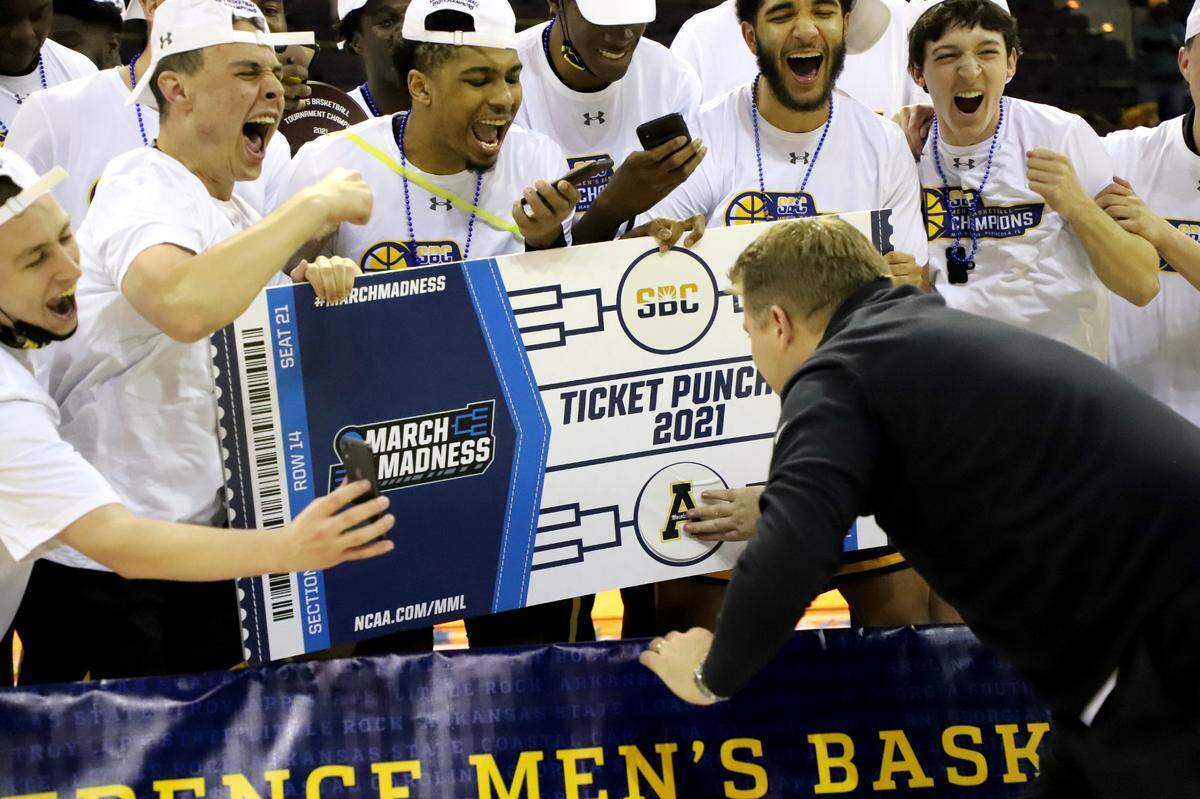 Appalachian State basketball coach Dustin Kerns places the school logo on an oversized ticket, signifying that the school has had its “ticket punched” to the 2021 NCAA men’s basketball tournament. It will be App State’s first NCAA tournament appearance since 2000.