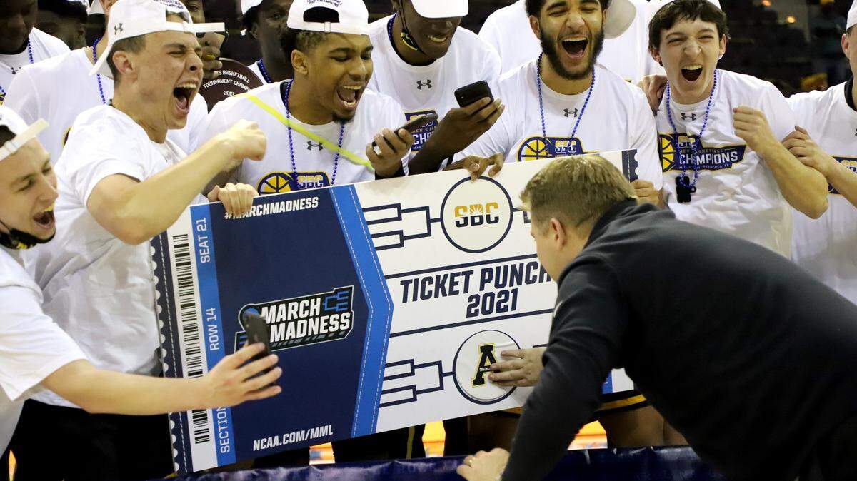 Appalachian State basketball coach Dustin Kerns places the school logo on an oversized ticket, signifying that the school has had its “ticket punched” to the 2021 NCAA men’s basketball tournament. It will be App State’s first NCAA tournament appearance since 2000.