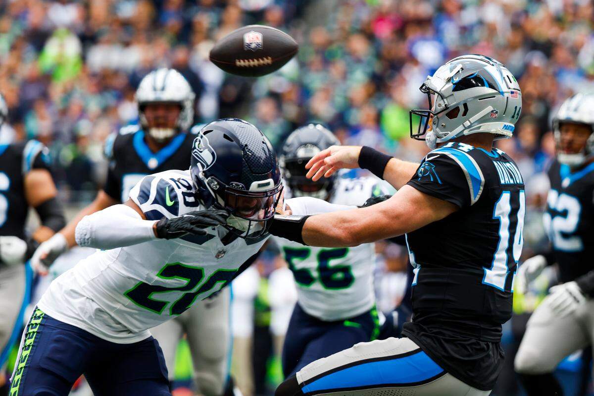Carolina Panthers quarterback Andy Dalton (14) passes before being hit by Seattle Seahawks safety Julian Love (20) during the first quarter at Lumen Field.