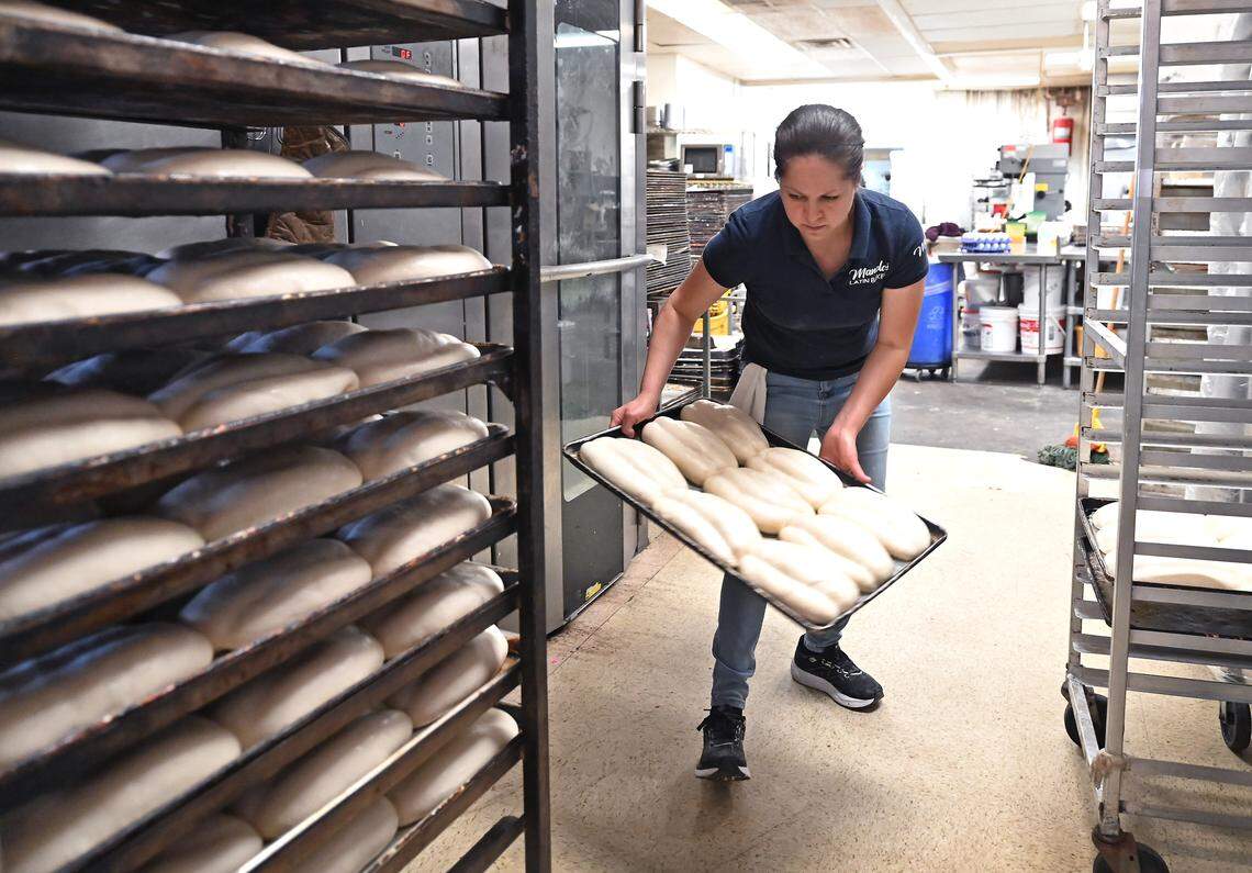 Manolo’s Latin Bakery employee Fior Tapia readies loaves of bread for baking on Friday.