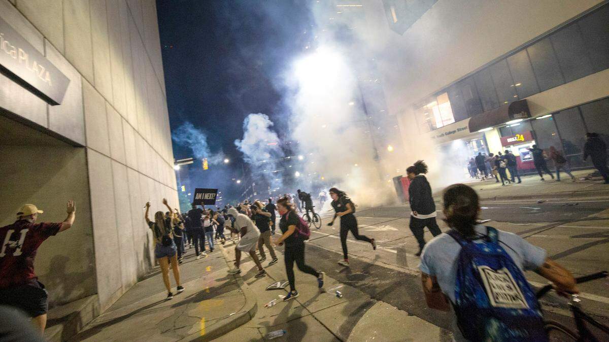 Protesters scramble on Fourth Street as police fire tear gas on either side of the protesters in uptown Charlotte on June 2, 2020.
