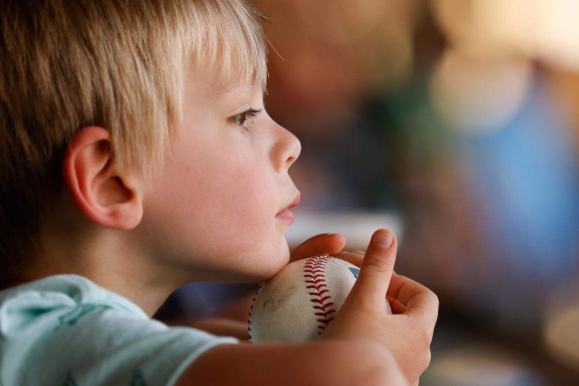Brennan Szudzik, 4, of Charlotte, leans over a home run ball that sailed over center field during a game between the Charlotte Knights and Memphis Redbirds at Truist Field in April.
