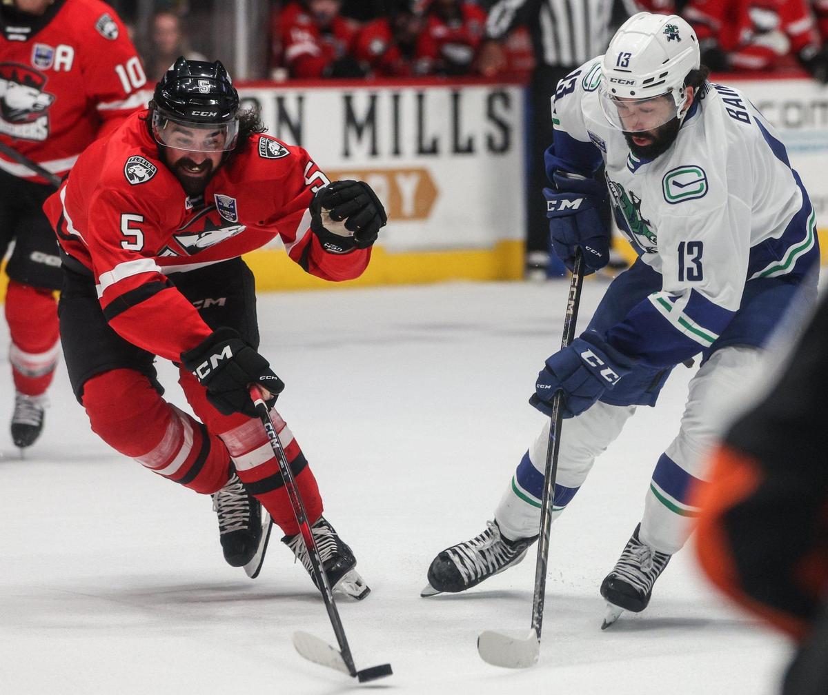 Checkers defender Trevor Carrick, left, and Canucks left winger Arshdeep Bains vie for control of the puck during the Calder Cup opening game at Bojangles Coliseum in Charlotte, NC on Friday, June 13, 2025. The Canucks won the first game, 4-3, after two overtime periods.