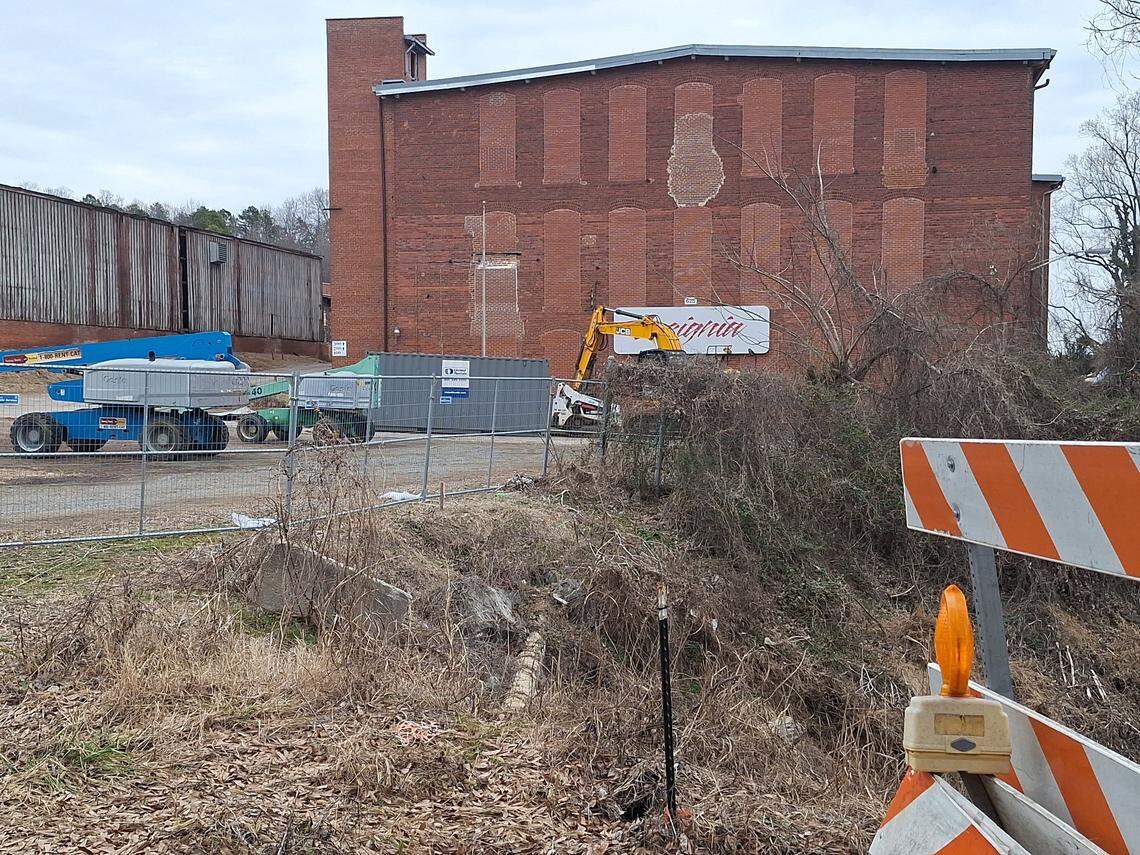 Dump trucks and front-end loaders sit outside the under-renovation former Warren C. Coleman mill in Concord on Feb. 2, 2025. Barricades blocked Main Street SW to through-traffic outside the building.