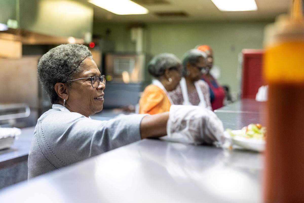 Patricia White hands off a plate of food as she and the women's ministry at Friendship Missionary Baptist Church serve meals at The Salvation Army Center of Hope in Charlotte, N.C., on Wednesday, October 22, 2025.