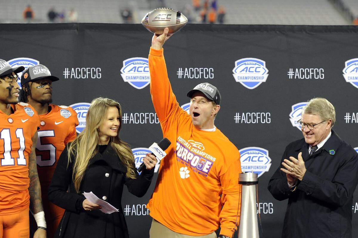 Clemson head coach Dabo Swinney, center, celebrates the Tigers’ fifth straight ACC football championship Saturday night. ACC commissioner John Swofford (right) and the ACC Network’s Kelsey Riggs flank Swinney.