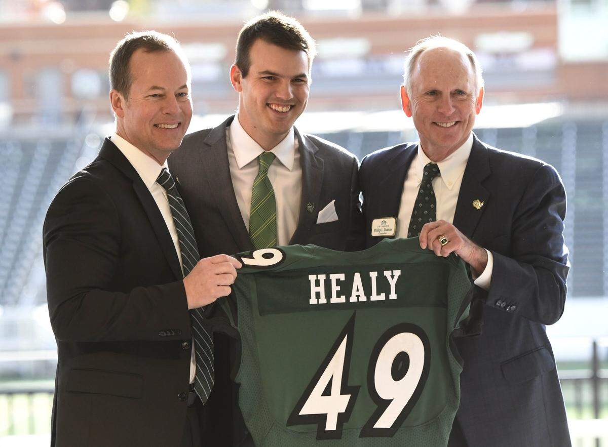 UNC Charlotte 49ers’ Director of Athletics Mike Hill, left, and Chancellor Phil Dubois, right, present new football coach Will Healy with a jersey during his introductory news conference at Richardson Stadium on Wednesday, December 5, 2018.