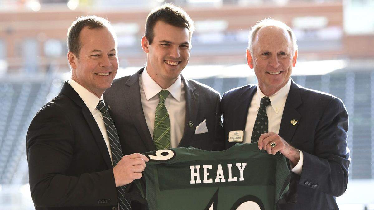 UNC Charlotte 49ers’ Director of Athletics Mike Hill, left, and Chancellor Phil Dubois, right, present new football coach Will Healy with a jersey during his introductory news conference at Richardson Stadium on Wednesday, December 5, 2018.