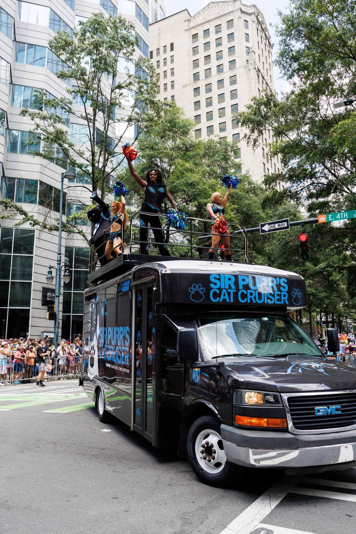 Members of the Charlotte Panthers TopCats Cheerleaders dance on top of a van painted in the Panthers team colors during the Charlotte Pride Festival & Parade on Sunday, Aug. 18, 2024