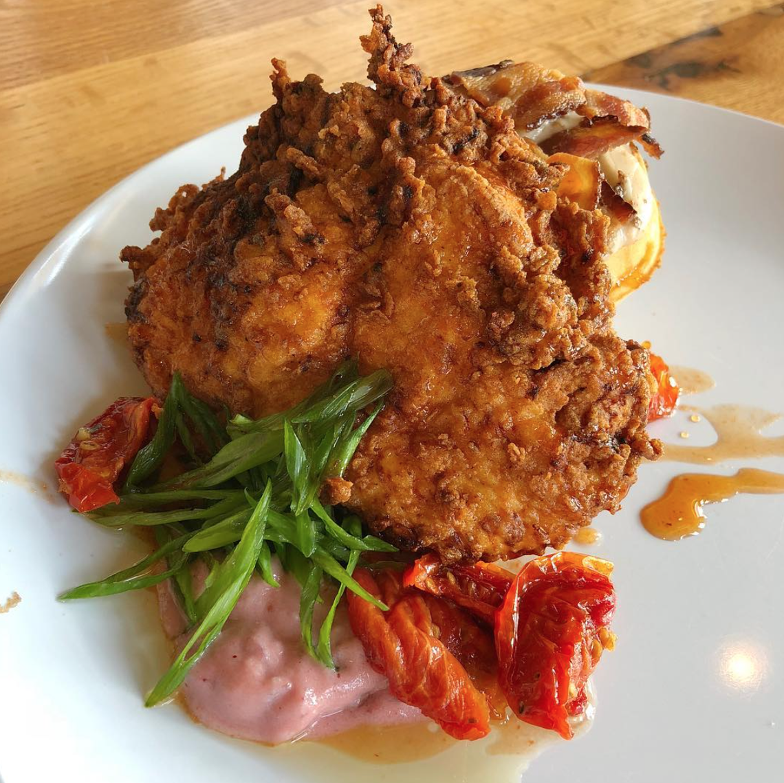 At River’s Edge, order Chicken & Waffles with sausage gravy, chèvre, roasted tomato, bacon and ancho honey.