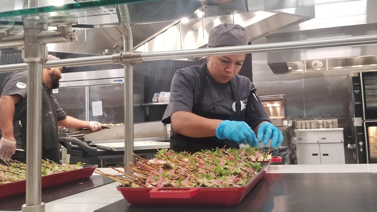 A chef arranges Peruvian chicken skewers for employees at Wells Fargo during the grand opening of the new food hall.