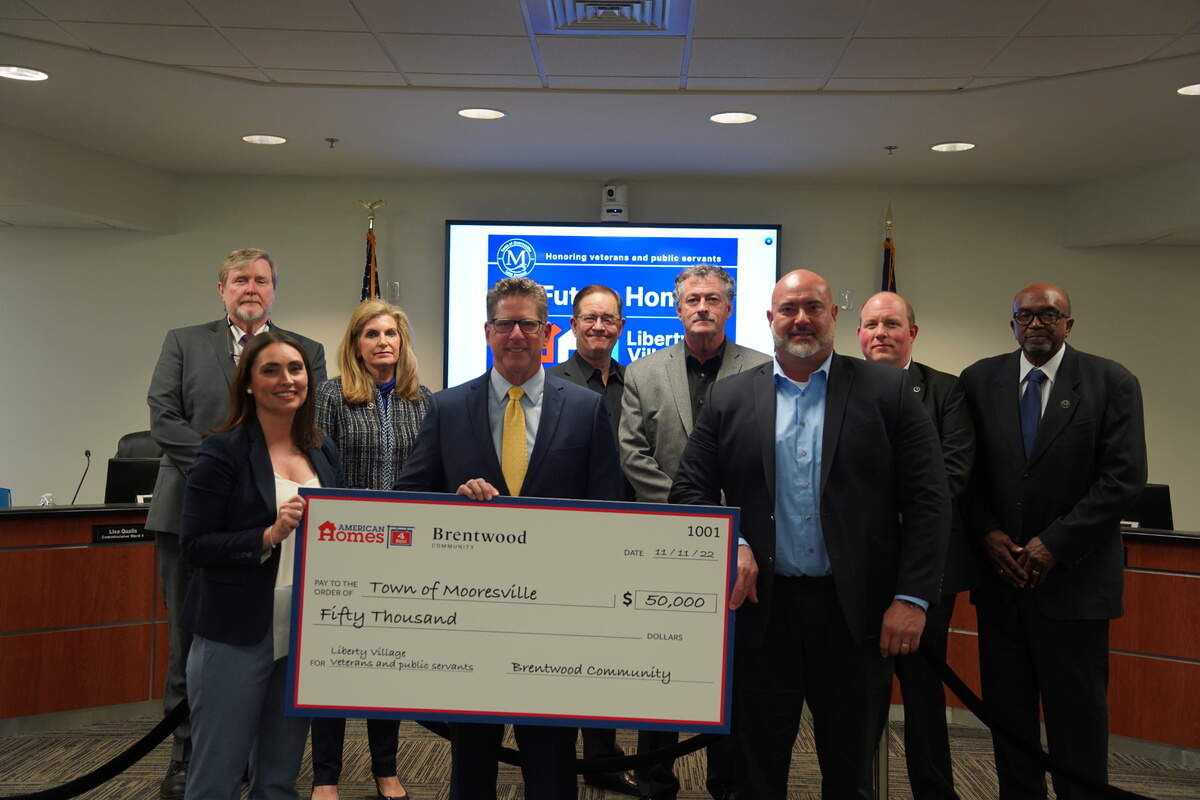 Cisco Garcia, senior vice president of development for American Homes 4 Rent, at right, and Brandi Donaldson, vice president of the Carolinas region for the company, at left, presented a check to Mooresville Mayor Miles Atkins and the Mooresville Board of Commissioners at the town board meeting on Monday, Nov. 21, 2022.                 