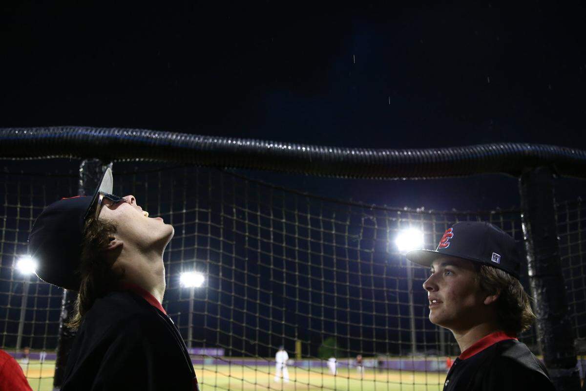Charlotte Catholic’s Miles Ziemer, left, watches rain fall on his glasses while Tripp Warnement looks on during the seventh inning against the Cox Mill Chargers at Cox Mill High School in Concord on May 13, 2024.