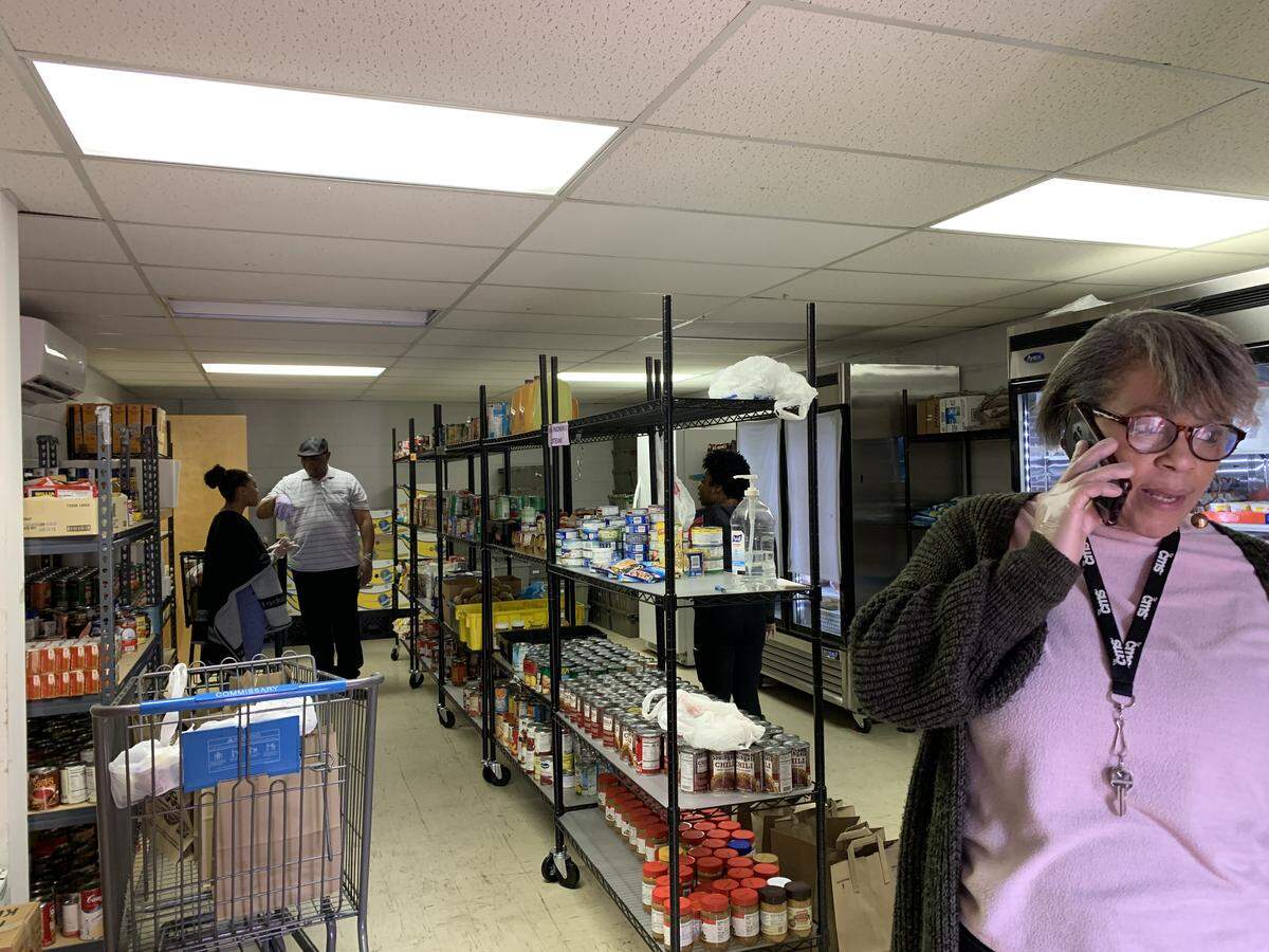 Shelbra Booth, pantry coordinator at the Loaves & Fishes location at 5318 Salem Church Road, talks on the phone on Saturday, March 14, 2020, about extra precautions the pantry is taking to prevent the spread of COVID-19. Volunteers are wearing gloves and packing bags, rather than have clients shop for their items.