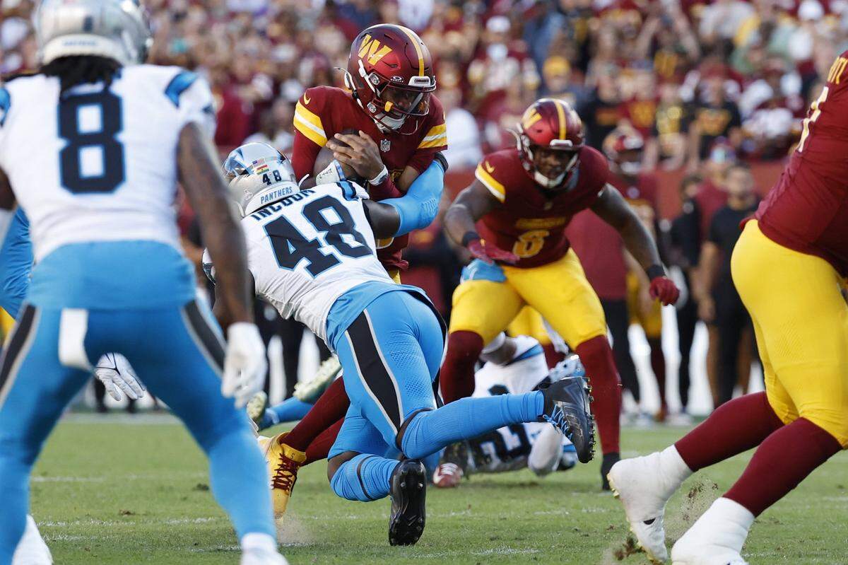 Oct 20, 2024; Landover, Maryland, USA; Washington Commanders quarterback Jayden Daniels (5) is tackled by Carolina Panthers linebacker Thomas Incoom (48) during the first quarter at Northwest Stadium. Mandatory Credit: Geoff Burke-Imagn Images