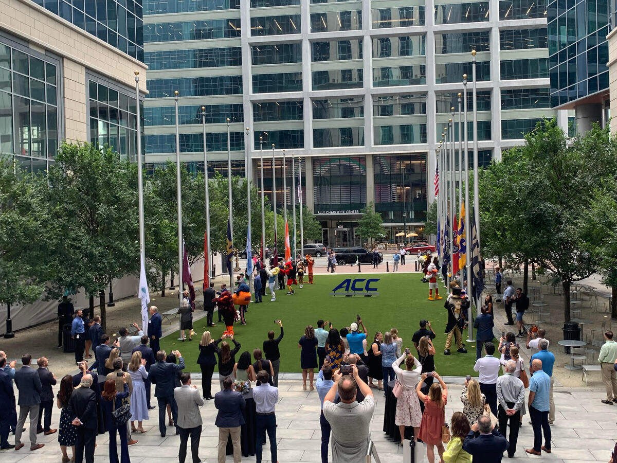 Crowds watch as flags representing all ACC member schools are raised outside the conferences new Charlotte headquarters, at the Bank of America Tower in the Legacy Union complex.