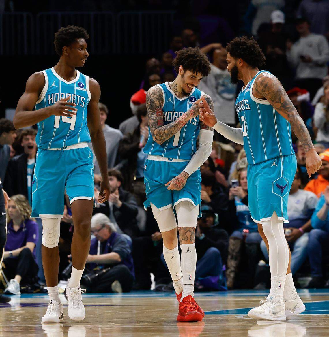 Hornets players LaMelo Ball, center, and Miles Bridges celebrate an assisted dunk during the game against the Wizards at Spectrum Center in Charlotte on Dec. 23, 2025. The Hornets defeated the Wizards 126-109.