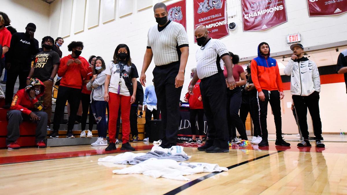 Official Brian White, center, examines water on the court during a game between Butler and Independence at Butler High School in Matthews, N.C. Friday, Feb. 11, 2022. The game was suspended due to a water leak with 3:49 left in the second quarter. Butler was leading Independence 19-14.