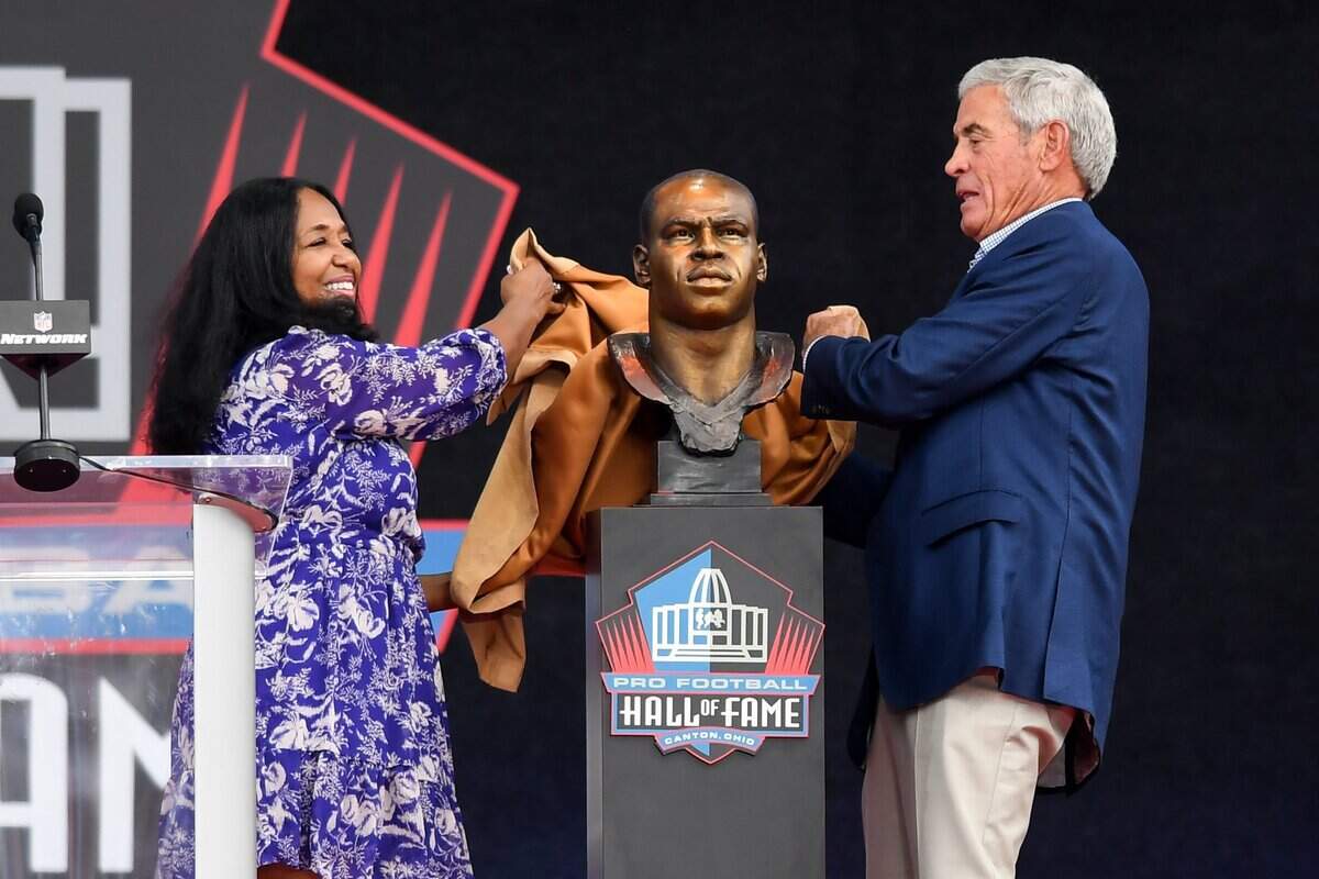 CANTON, OHIO - AUGUST 06: Melanie Mills (L) and former NFL head coach Jim Mora unveil the bronze bust for Sam Mills during the 2022 Pro Hall of Fame Enshrinement Ceremony at Tom Benson Hall of Fame Stadium on Aug. 6, 2022 in Canton, Ohio. (Photo by Nick Cammett/Getty Images)
