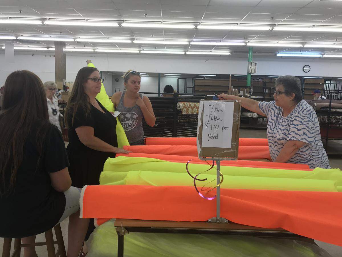 Jeannie Guffey (right) helps Carla McSwain (second from left) pick out a bolt of florescent waterproof fabric during one of Mary Jo’s Cloth Store’s final days.
