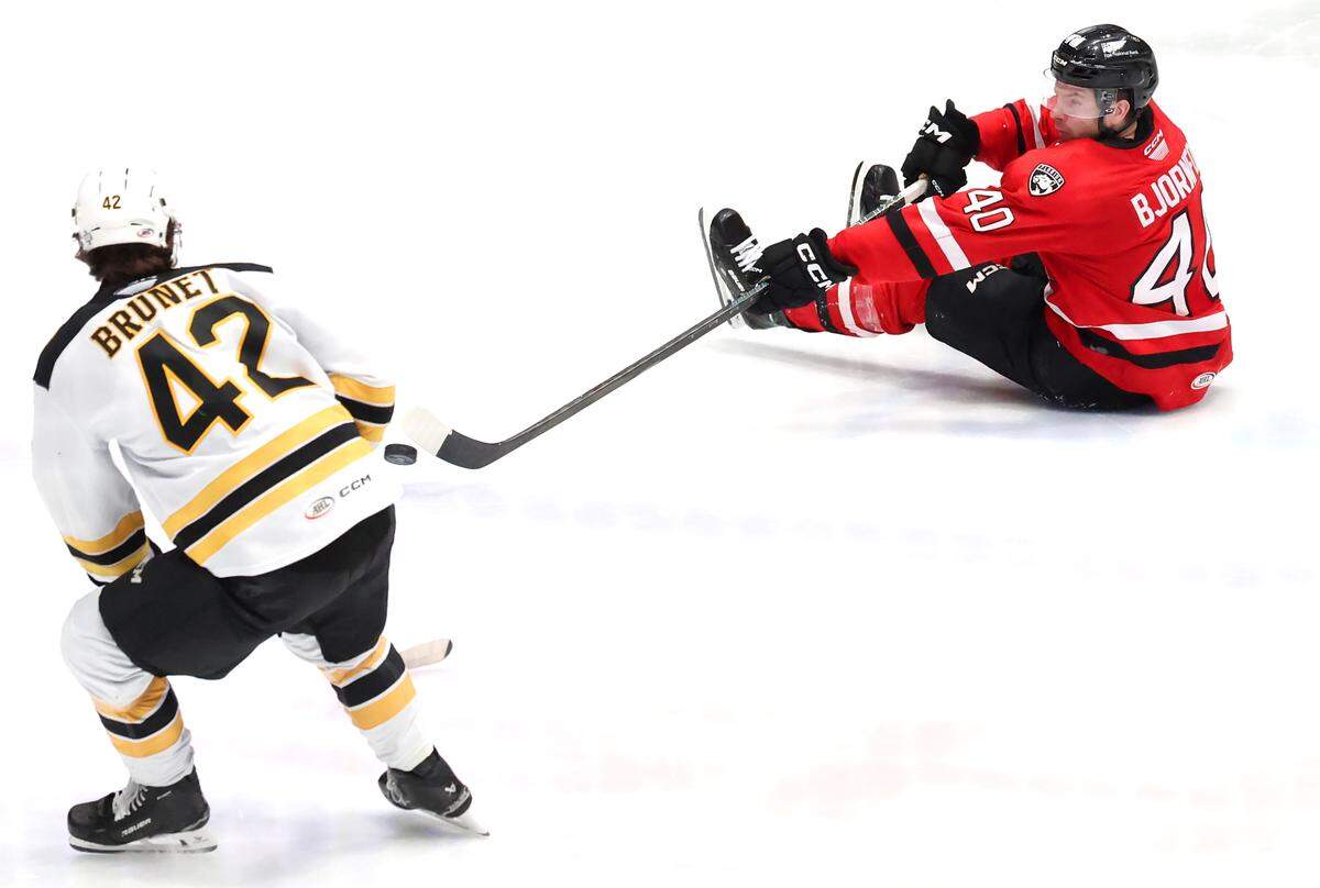Charlotte Checkers Tobias Bjornfot, right, attempts to pass the puck to a teammate as he slides across the ice as Providence Bruins Frederic Brunet, left, looks on during action on Wednesday, May 7, 2025. The Providence Bruins defeated the Charlotte Checkers 3-2.