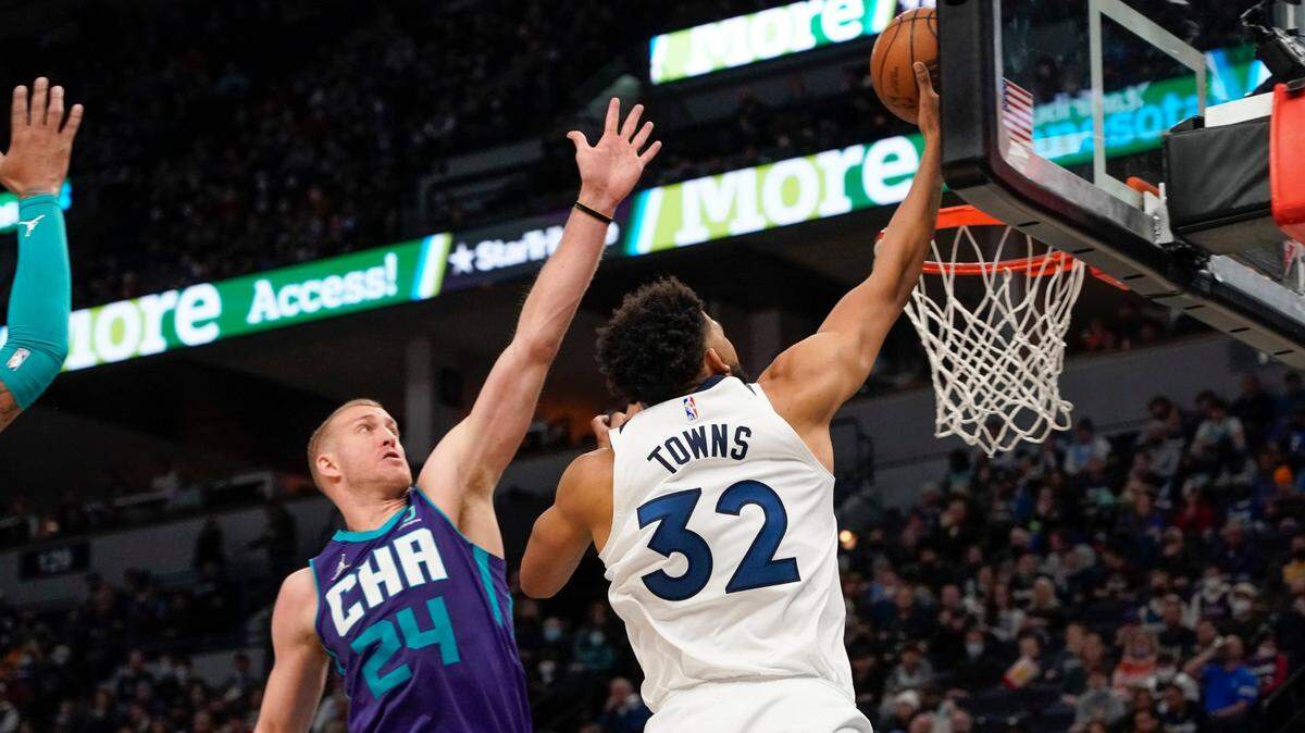 Minnesota Timberwolves center Karl-Anthony Towns (32) goes up for a shot past Charlotte Hornets center Mason Plumlee (24) during the first half of an NBA basketball game Tuesday, Feb. 15, 2022, in Minneapolis. (AP Photo/Craig Lassig)