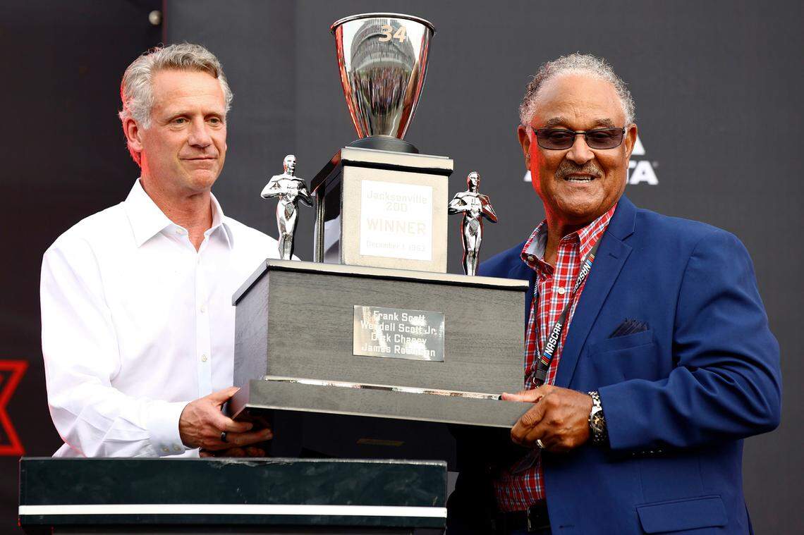 NASCAR President Steve Phelps, left, presents the family of NASCAR Hall of Fame driver Wendell Scott with a trophy for the 1963 Jacksonville 200 win onstage prior to the NASCAR Cup Series Coke Zero Sugar 400 at Daytona International Speedway on Saturday, Aug. 28, 2021, in Daytona Beach, Fla.