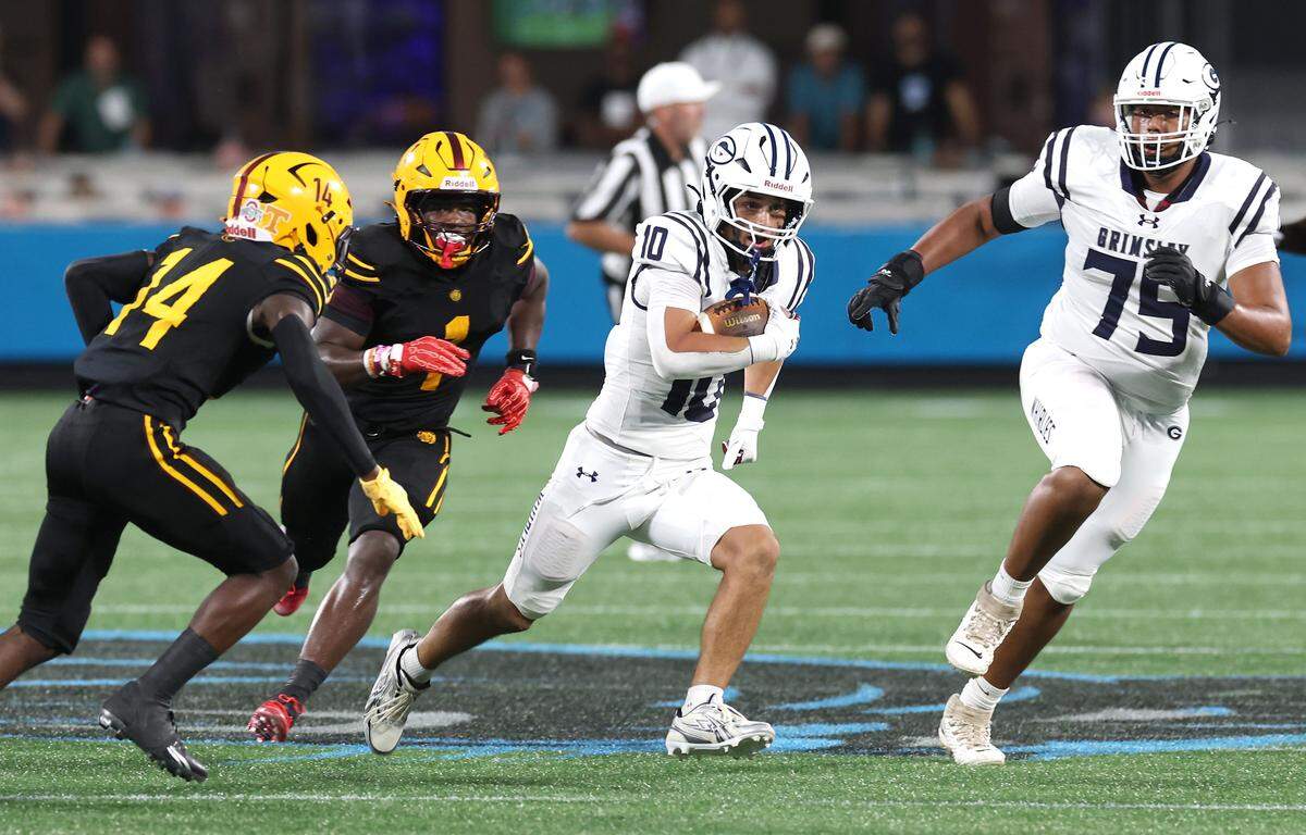 Grimsley Whirlies wide receiver Hudson Cooper breaks past two West Charlotte Lions defenders for a touchdown during the Keep Pounding Classic at Bank of America Stadium on Friday, August 22, 2025.