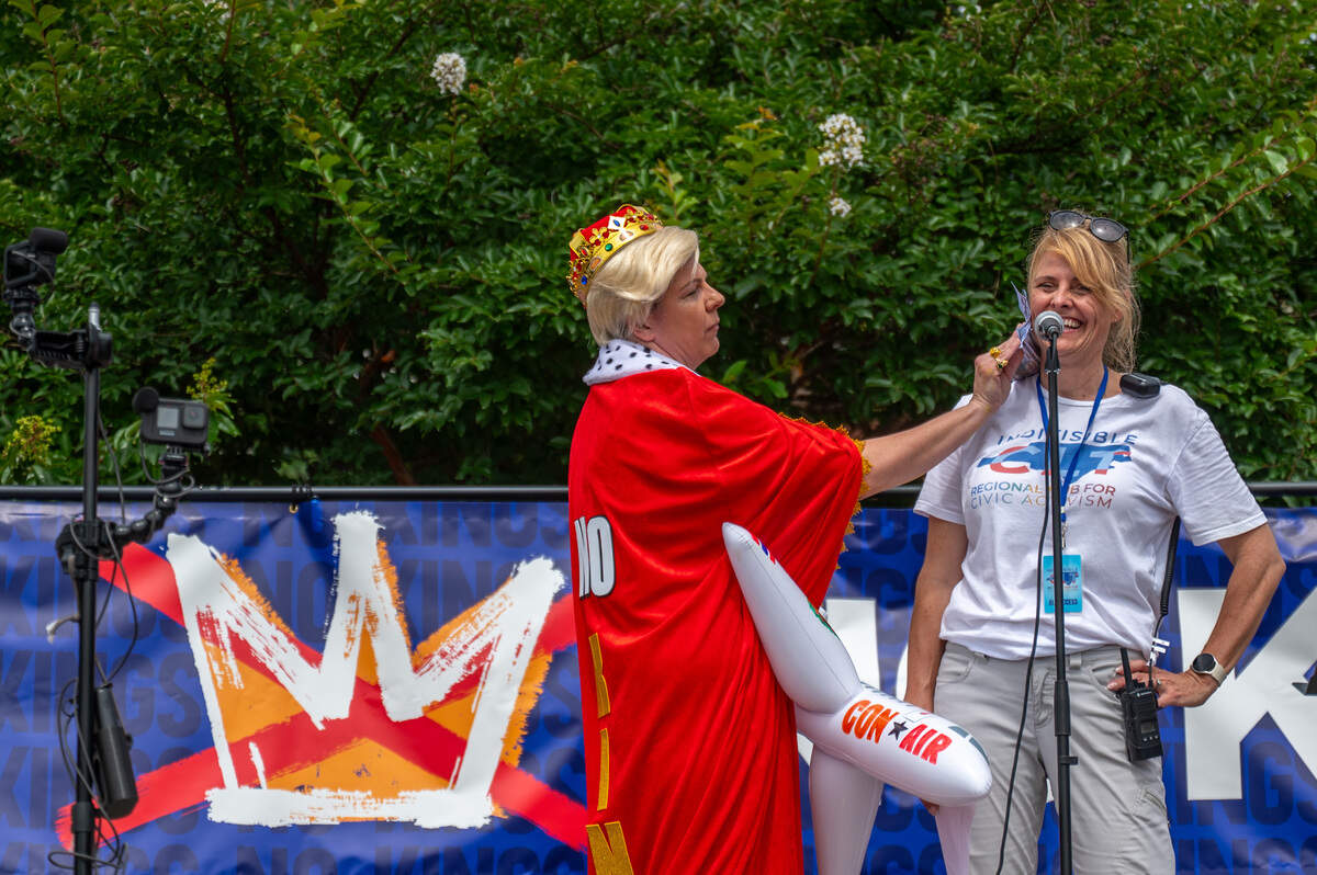 Amanda Hancock dressed like President Trump brushes speaker Carolyn Everly with fake money at the No Kings march and rally at First Ward Park in Charlotte, NC, Saturday, June 14, 2025.