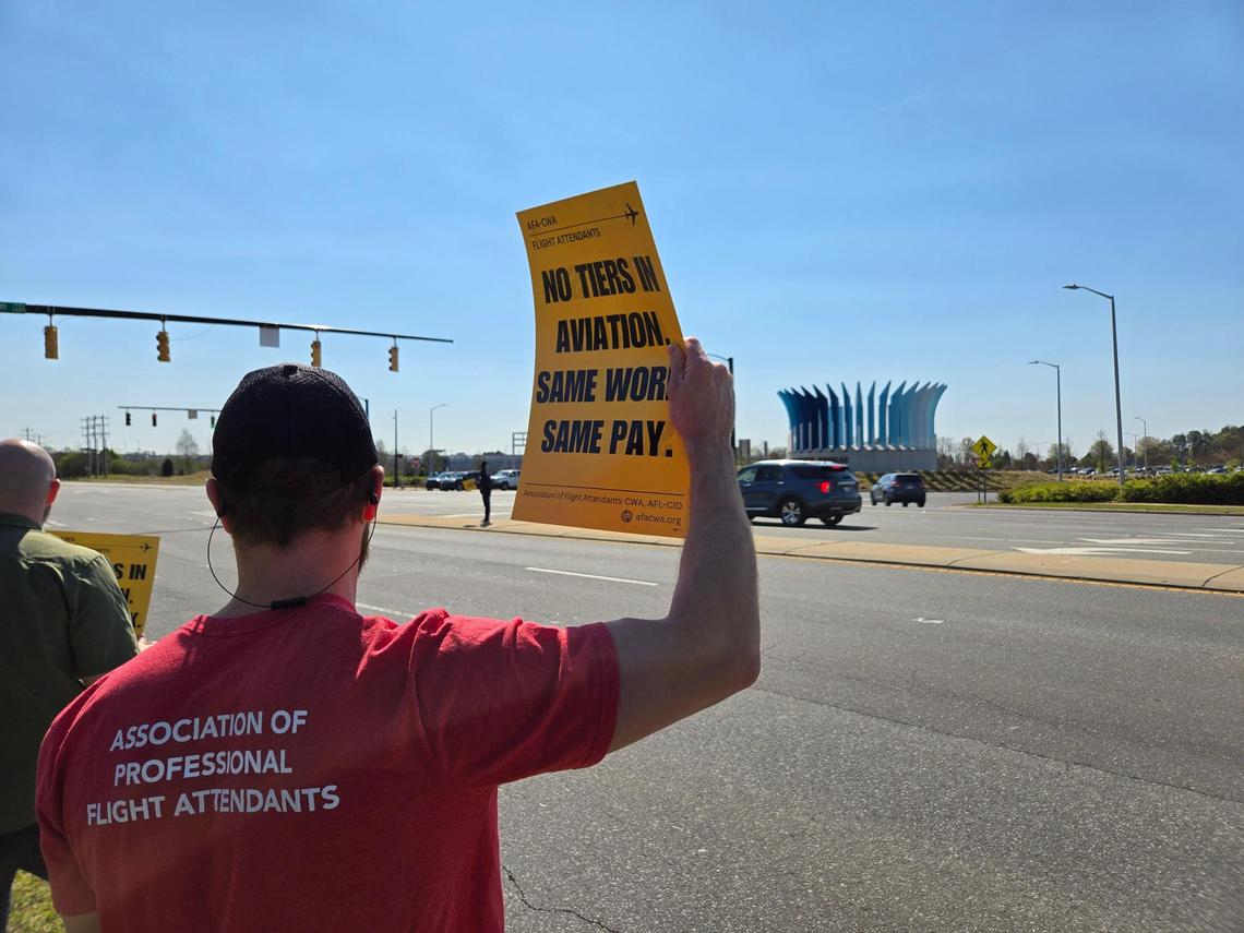 A protester holds up a sign showing support for flight attendants outside of Charlotte Douglas International Airport.