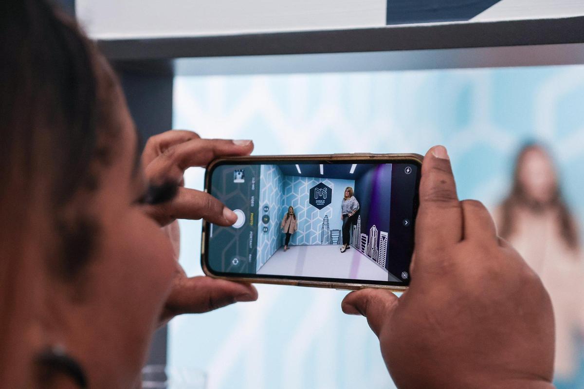 A museum employee takes a photo of attendees in the Ames room, which gives the illusion of two people being significantly different heights while standing on opposite walls, at the Museum of Illusions Charlotte.