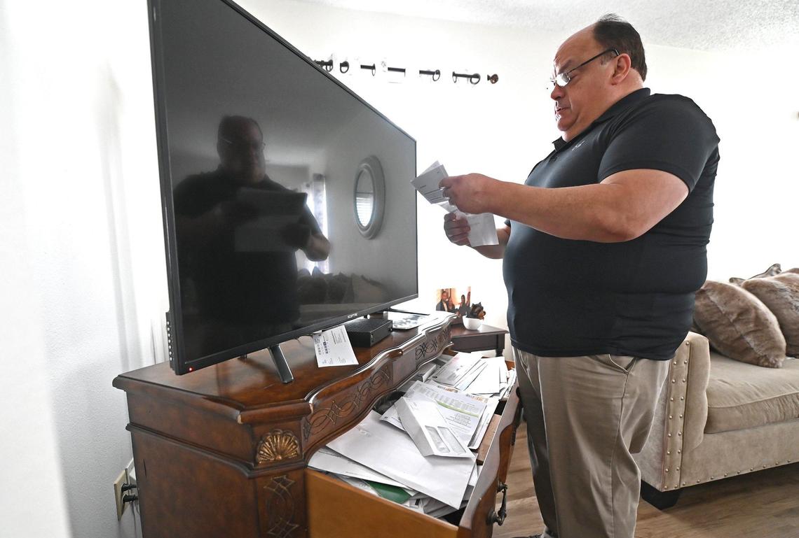 Alex Montalvo looks through his medical bills at his home in Waxhaw. Although he has health insurance, Montalvo has been saddled with thousands of dollars of debt from Atrium Health. That has damaged his credit.