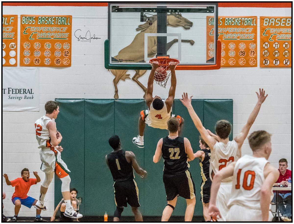 Former East Lincoln star Sidney Dollar dunks the ball as his baby brother, Jaxon, left (in orange shirt) celebrates