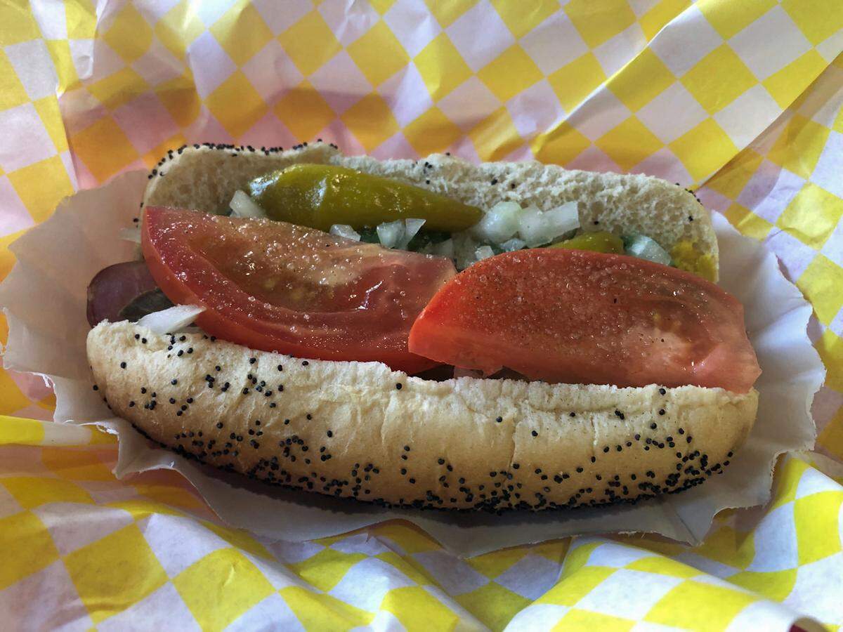 Matt’s Chicago Dogs are served on a poppy seed bun topped with chopped onions, tomato wedges, green relish, yellow mustard, a pickle spear, peppers and a dash of celery salt.