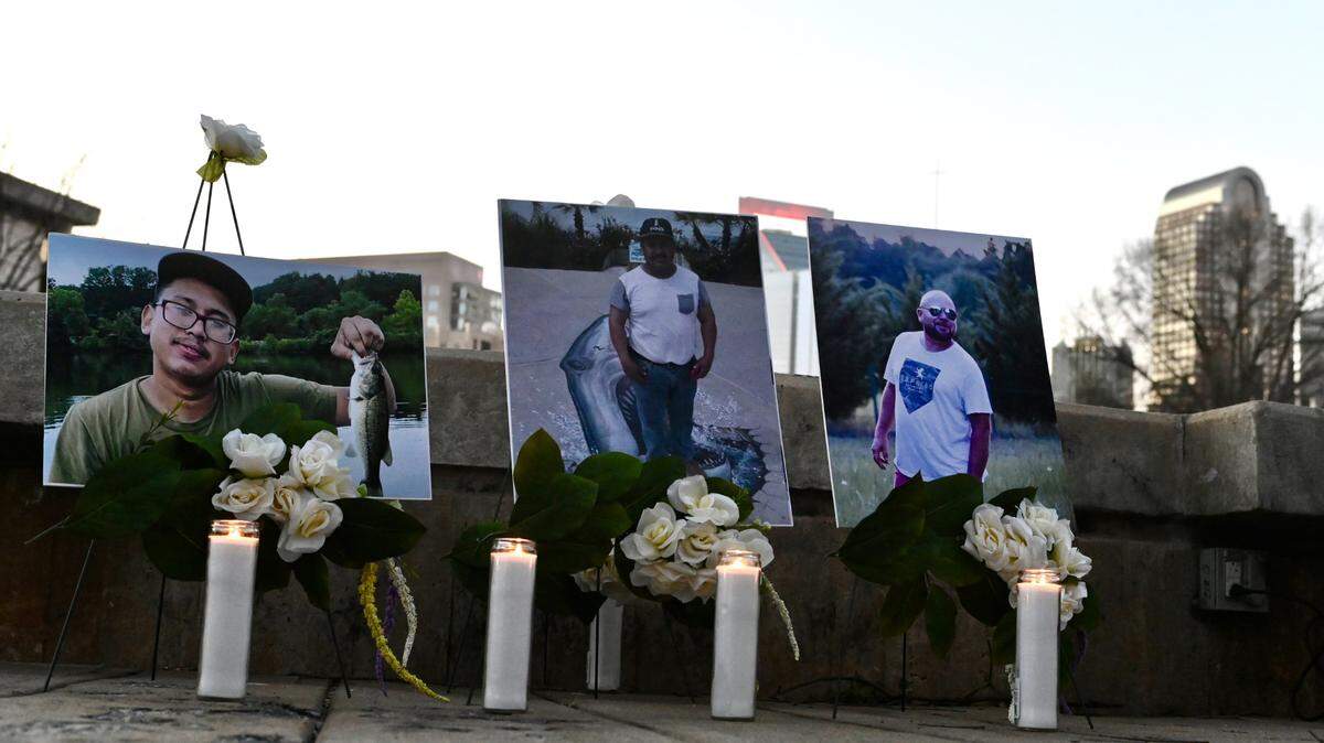 Candles are lit below the photographs of the three men who died when the scaffolding collapsed at a Charlotte, NC construction site in early January 2023. Friends and family gathered on Friday, February 3, 2023 at Marshall Park for a candlelight vigil.