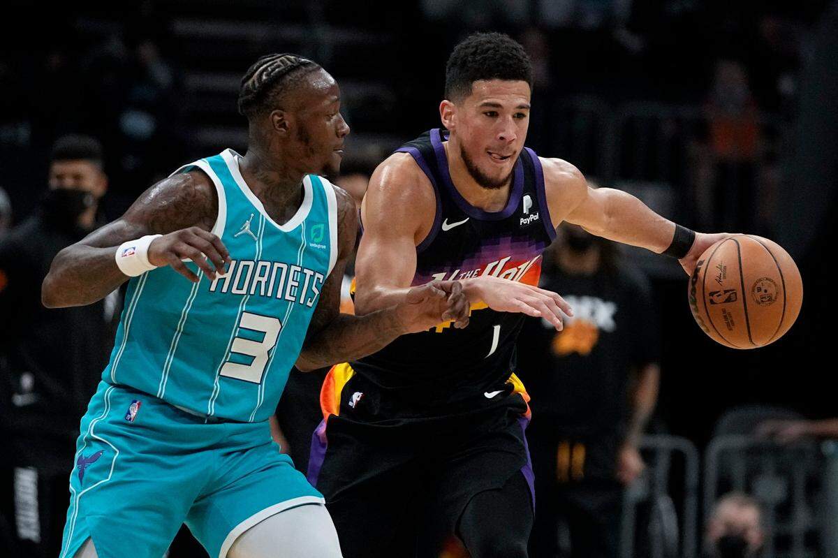 Phoenix Suns guard Devin Booker drives to the basket past Charlotte Hornets guard Terry Rozier during the first half of an NBA basketball game on Sunday, Jan. 2, 2022, in Charlotte, N.C. Phoenix won, 133-99.