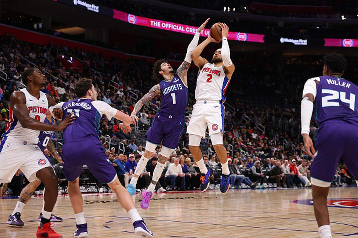 Cade Cunningham of the Detroit Pistons tries to get a shot off next to LaMelo Ball of the Charlotte Hornets during the first half at Little Caesars Arena in Detroit, Michigan.