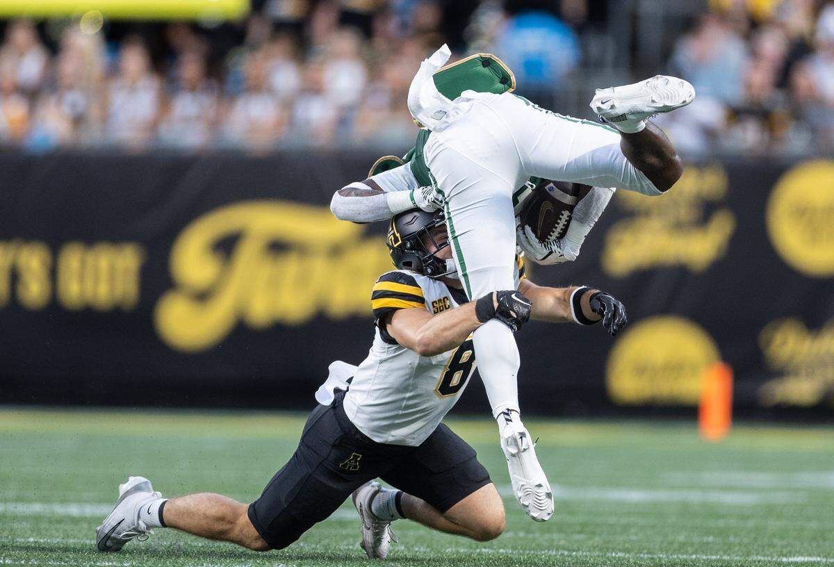 Appalachian State Mountaineers defensive back Dylan Hasz, bottom, takes down Charlotte 49ers running back CJ Stokes during the Duke's Mayo Classic at the Bank of America Stadium in Charlotte on Friday, August 29, 2025.