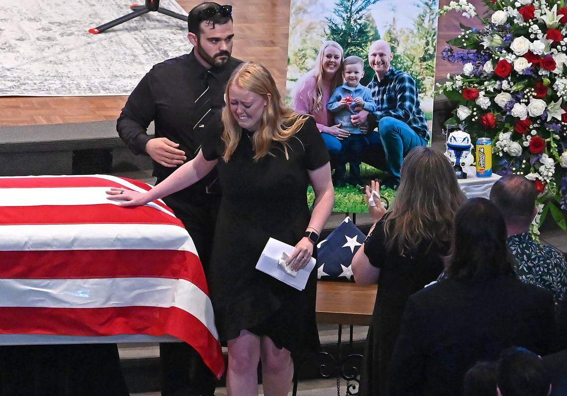Ashley Eyer places her hand on her husband Joshua Eyer’s casket after making remarks to mourners at First Baptist Church on Friday, May 3, 2024. Officer Eyer died from wounds sustained during a standoff with a gunman on Monday, April 29th. Three other law enforcement officers were also killed in the shootout.